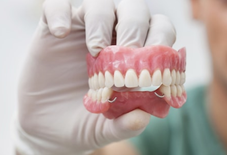 hand with gloves holding dentures